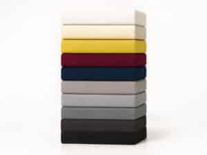Stack of ten colored fitted sheets in white, cream, yellow, red, blue, gray and black