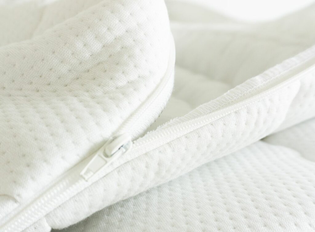 Detailaufnahme eines weißen Matratzenbezugs aus Tencel mit Reißverschluss und strukturierter Oberfläche.