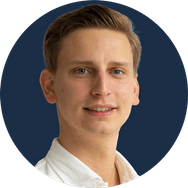 Ein junger Mann mit kurzem, blonden Haar lächelt freundlich in einem weißen Oberteil vor einem neutralen Hintergrund.