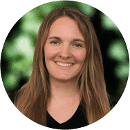 Eine lächelnde Frau mit langen, braunen Haaren, die ein schwarzes Oberteil trägt.