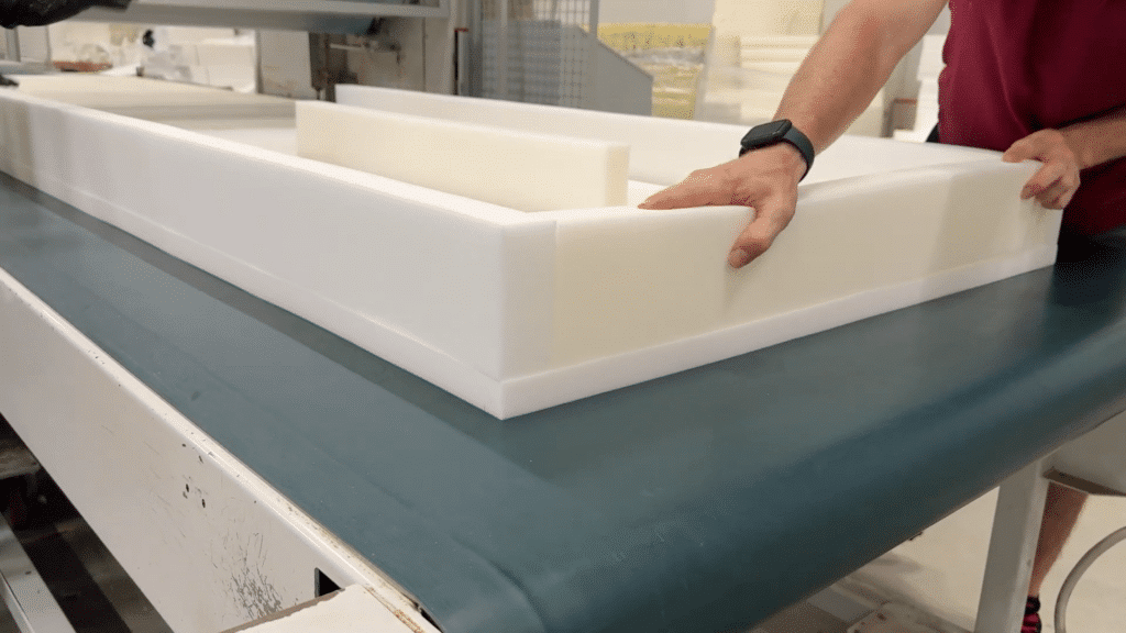 Eine Person montiert eine Matratze aus weißen Schaumstoffelementen auf einer Arbeitsfläche.