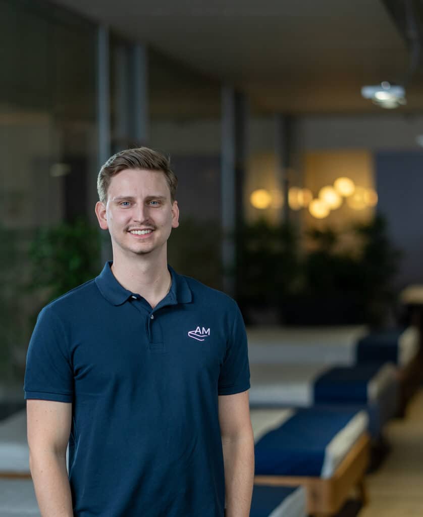 Mann in blauer Polo mit Logo, im Innenraum.