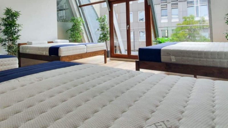 Mehrere Matratzen in einem modernen Raum mit großen Fenstern, aus Tencel, in verschiedenen Größen und Designs.