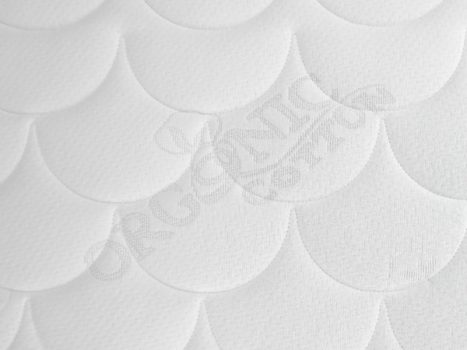 Detailansicht einer weißen, gesteppten Oberfläche aus Bio-Baumwolle mit schuppenförmigem Muster.