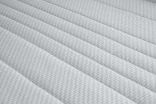 Eine weiße, gestreifte Matratze mit strukturiertem Bezug, die eine gleichmäßige Oberfläche zeigt.