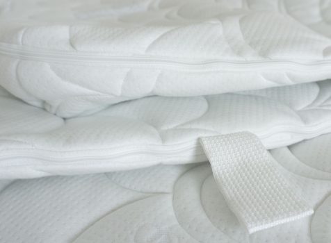 Detailaufnahme eines weißen Matratzenbezugs aus Bio-Baumwolle mit Reißverschluss und Tragegriff.
