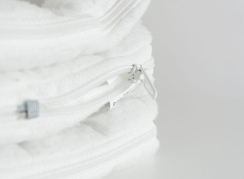 Detailaufnahme eines weißen Matratzenbezugs mit Reißverschluss und weichem, gepolstertem Material.